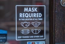 A decal on a glass window reads "MASK REQUIRED". Below the words are pictures of various types of masks.