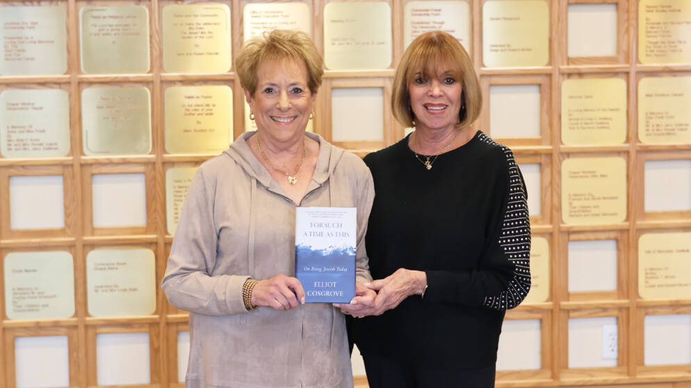 Two woman at a synagogue hold up a book