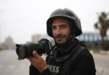 A journalist wearing a helmet and holding a camera