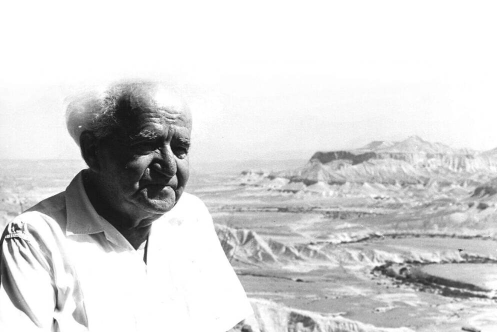 A man with white hair standing outdoors.