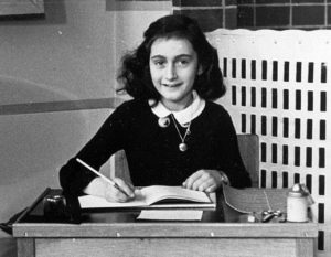 A black and white photo of anne frank at a desk