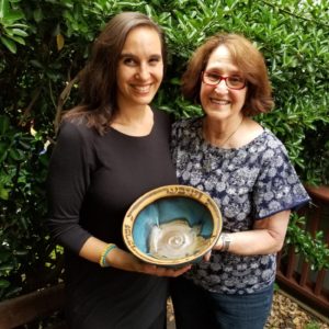 Sonia Gordon-Walinsky and her mother Nina Gordon hold a clay blessing bowl. The Hebrew words meaning “You shall eat, be satisfied and bless” are written on the piece.