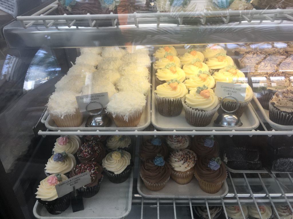 coconut cream, carrot cake and chocolate and vanilla cupcakes in a display case at Cake