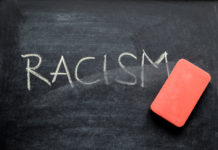 an eraser erasing the word racism on a chalkboard