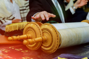 a hand hovers over a Torah scroll