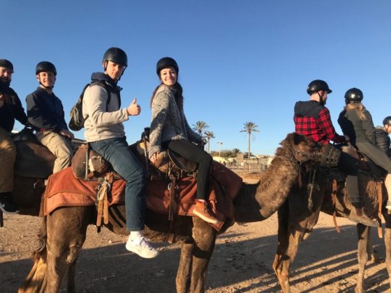 From left: Mick Baker and Delaney Rohde ride a camel in the desert.