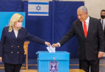 Benjamin and Sara Netanyahu drop their ballots into a ballot box