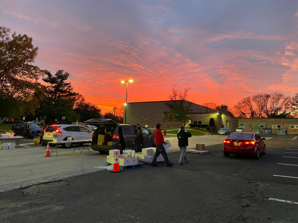 Sunset over a parking lot with two cars and people walking by