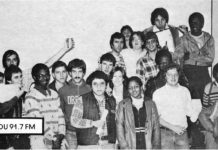 A black and white pictures shows several students from the radio station smiling; some are holding up cans.