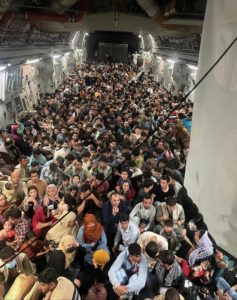Hundreds of people are crammed together in a large aircraft.