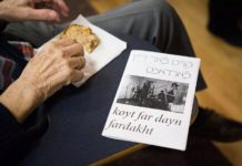On someone's lap is a piece of cake someone is picking at, as well as a program printed on white paper that reads "koyt far dayn fardakht," the name of a Yiddish anarchist punk band.