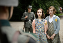 Standing with fear and apprehension in front of a Nazi soldier, Anne Franke and Hannah Goslar war wearing dresses and cardigans with shower-length, tidy hair.