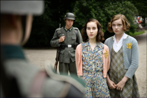 Standing with fear and apprehension in front of a Nazi soldier, Anne Franke and Hannah Goslar war wearing dresses and cardigans with shower-length, tidy hair.