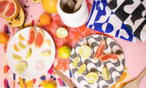 Plates of cute citrus lie on top of brightly colored and patterned beeswax wrappers.