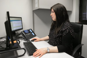 Dr. Chani Yondorf is a white woman with a dark brown sheitel sitting in front of a computer.