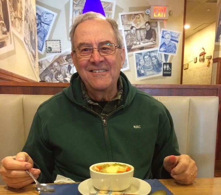 Howard Cohen is smiling at a restaurant and he has a bowl of soup.  