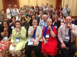 Rows of librarians pose for a photo with their fingers on their lips, making a shushing sound.