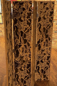 A wooden room divider is carved with floral ornamentation.