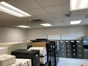A storage room is filled with boxes and black filing cabinets.