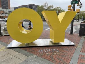 A big yellow sculpture with the letters "O" and "Y" sit on the brick entrance to the Weitzman National Museum of American Jewish History.