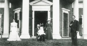 In a black and white picture, a family poses for a picture in front of Monticello.
