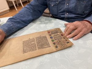 Mordechai Rosenstein holds a worn parchment scribed with neat and colorful Hebrew letters.