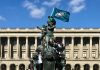 Standing on top of a bronze statue, Eagles fans in Jersey hold up an Eagles flag, their fists in the air.