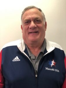 Lou Moyerman is an older white man with gray hair wearing a red, white and blue Adidas jacket.