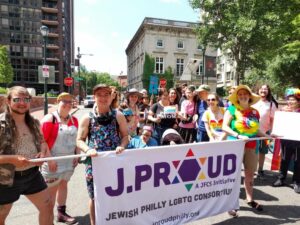 A group of people with a "J.PROUD" sign are standing outside.