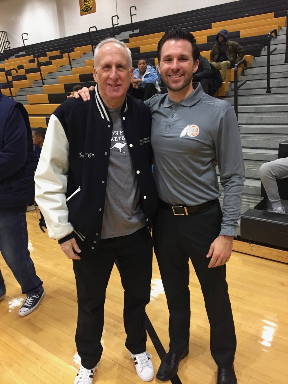 Two men pose together in a gymnasium